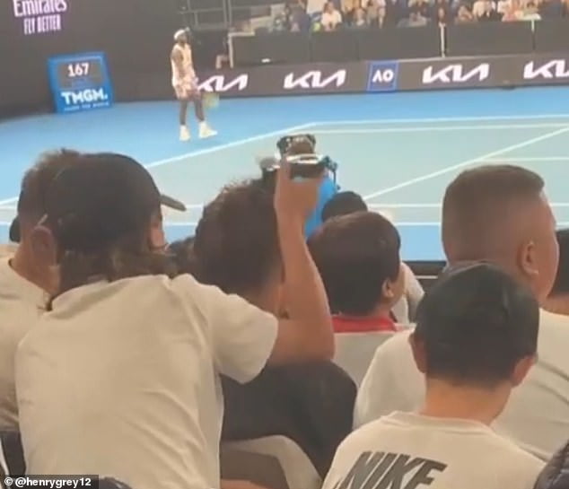American star Frances Tiafoe (top of frame) remained oblivious as some cheeky fans turned their courtside seats into a barber shop on Wednesday night