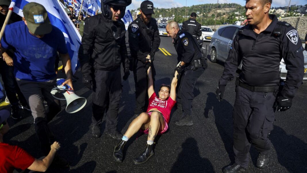 Members of the security forces remove a demonstrator blocking a highway to Jerusalem.