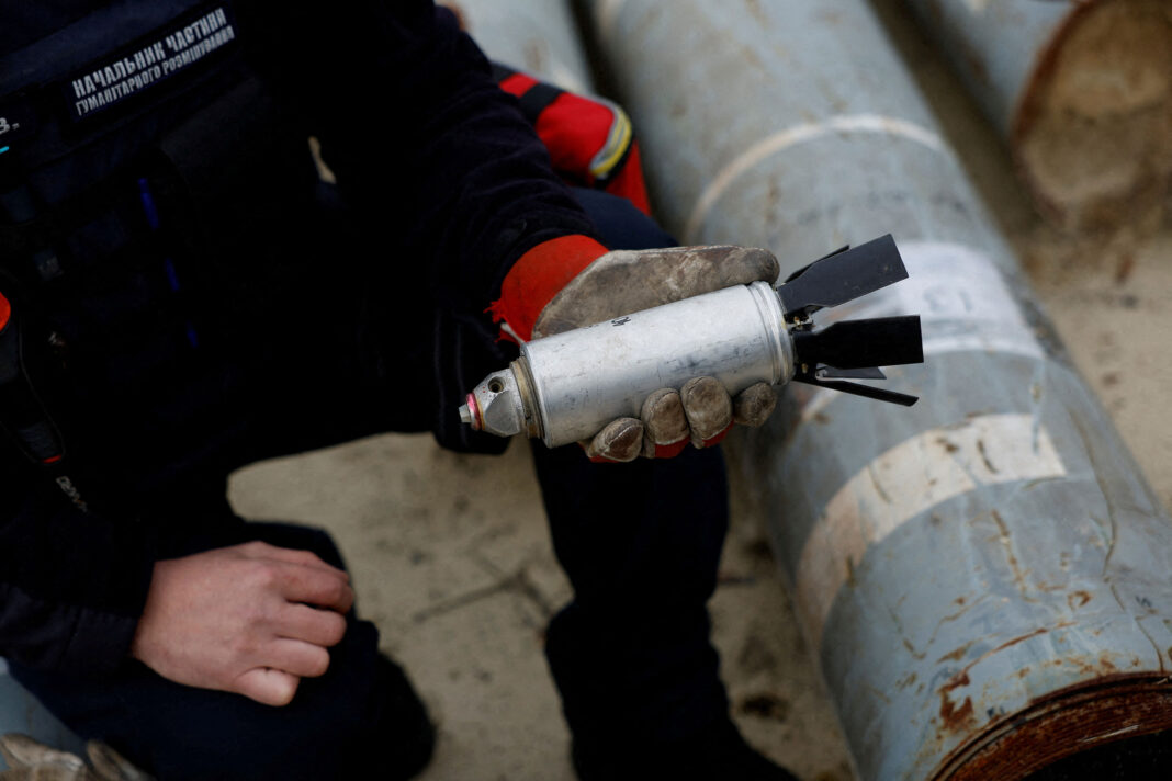 Ukrainian military serviceman Igor Ovcharruck holds a defused cluster bomb from an MSLR missile, among a display of pieces of rockets used by Russian army that a Ukrainian munitions expert said did not explode on impact, in Ukraine's Kharkiv region on October 21, 2022. 