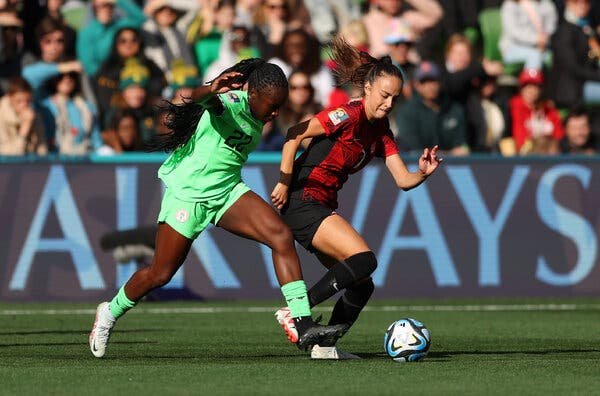 Michelle Alozie of Nigeria, at left in green, and Julia Grosso of Canada, in red, race behind the ball.