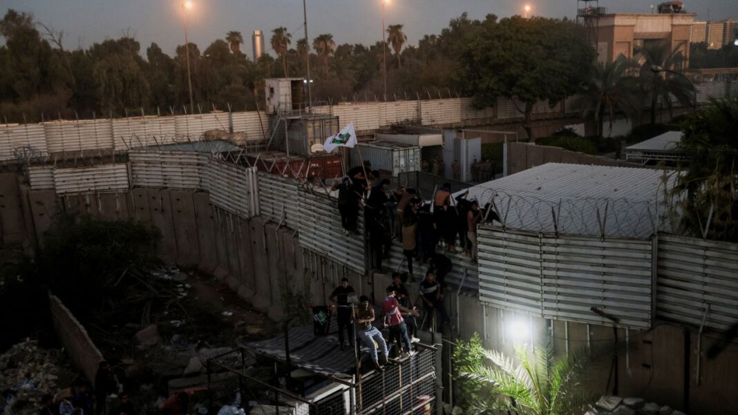 Protesters climb a fence as they gather near the Swedish embassy in Baghdad on Thursday. 