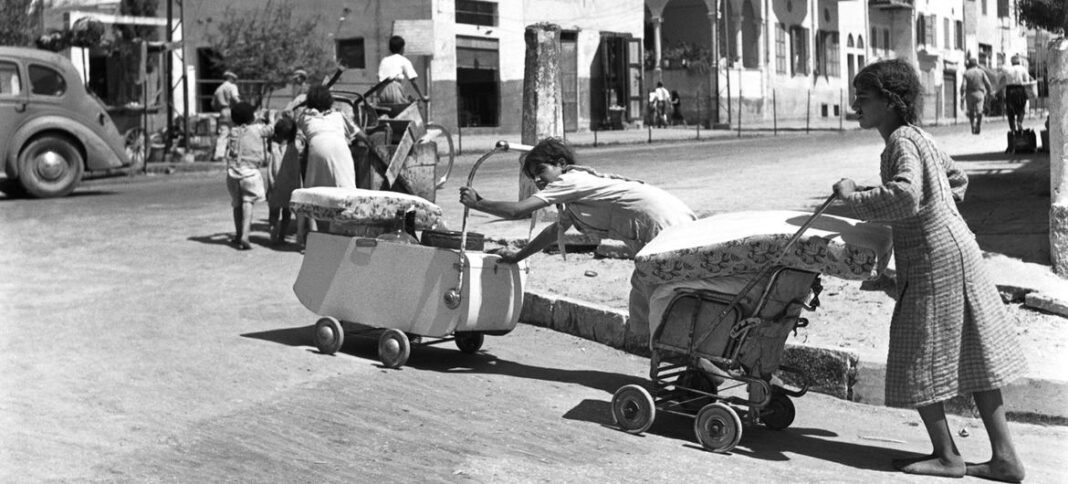 Barefoot and pushing their belongings in prams and carts, Arab families leave  the coastal town of Jaffa which became part of the greater Tel Aviv area in the state of Israel.