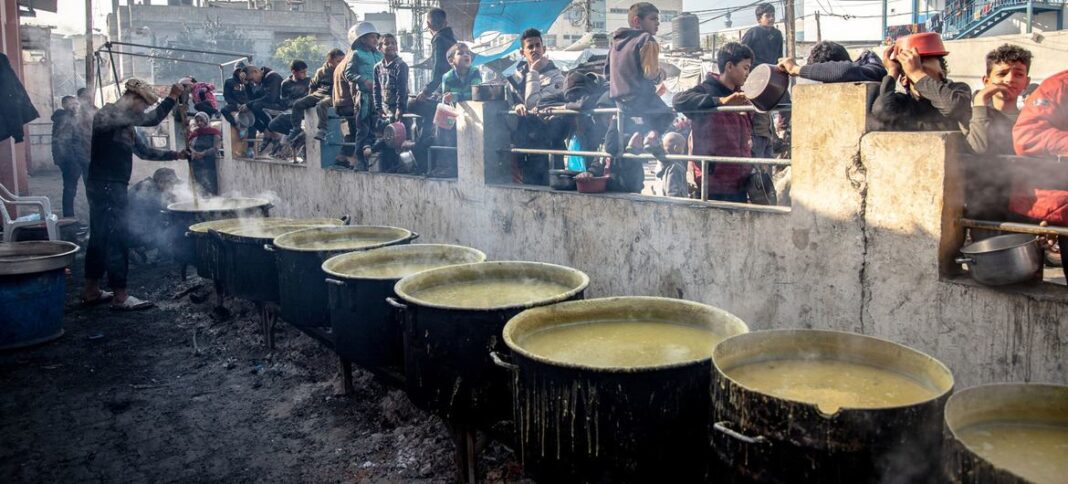 Displaced Palestinians wait for food at Al-Shaboura camp, in Rafah.